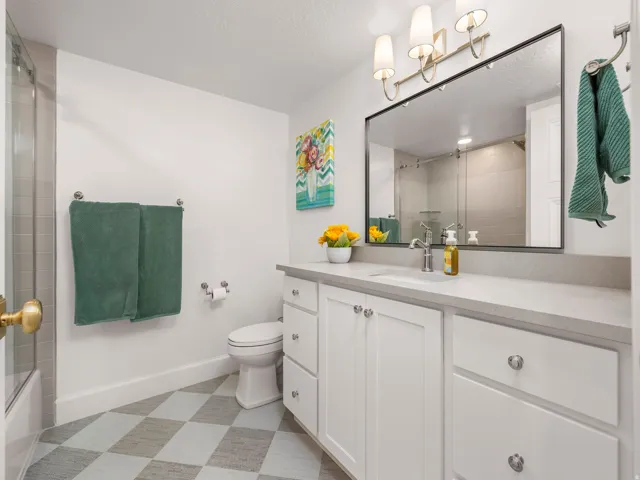 Bathroom featuring a white vanity with slab countertops, an undermount sink, and chrome hardware
