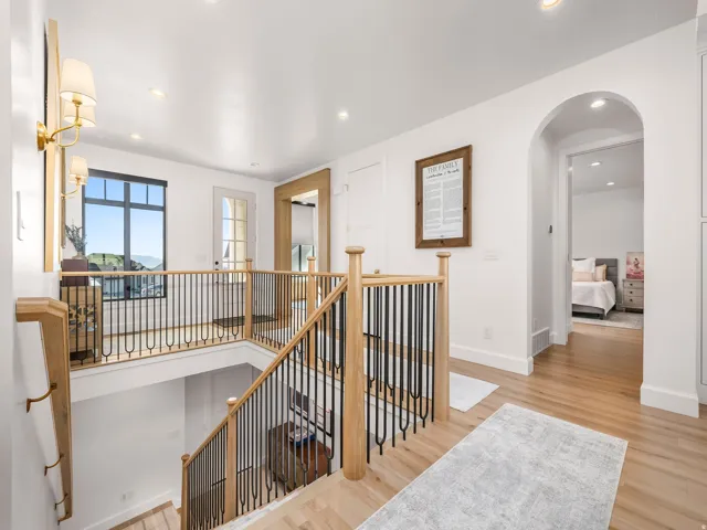 Hardwood flooring and a wood staircase with black iron balusters define this bright upper landing