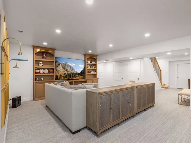 Entertainment space featuring a large built-in media center with wood-finish cabinetry, recessed lighting, carpet flooring, and a staircase with wood treads and a metal railing