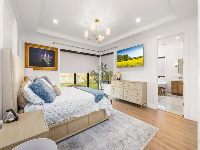 Spacious room featuring wood-finish flooring, a tray ceiling, and corner windows with roller shades