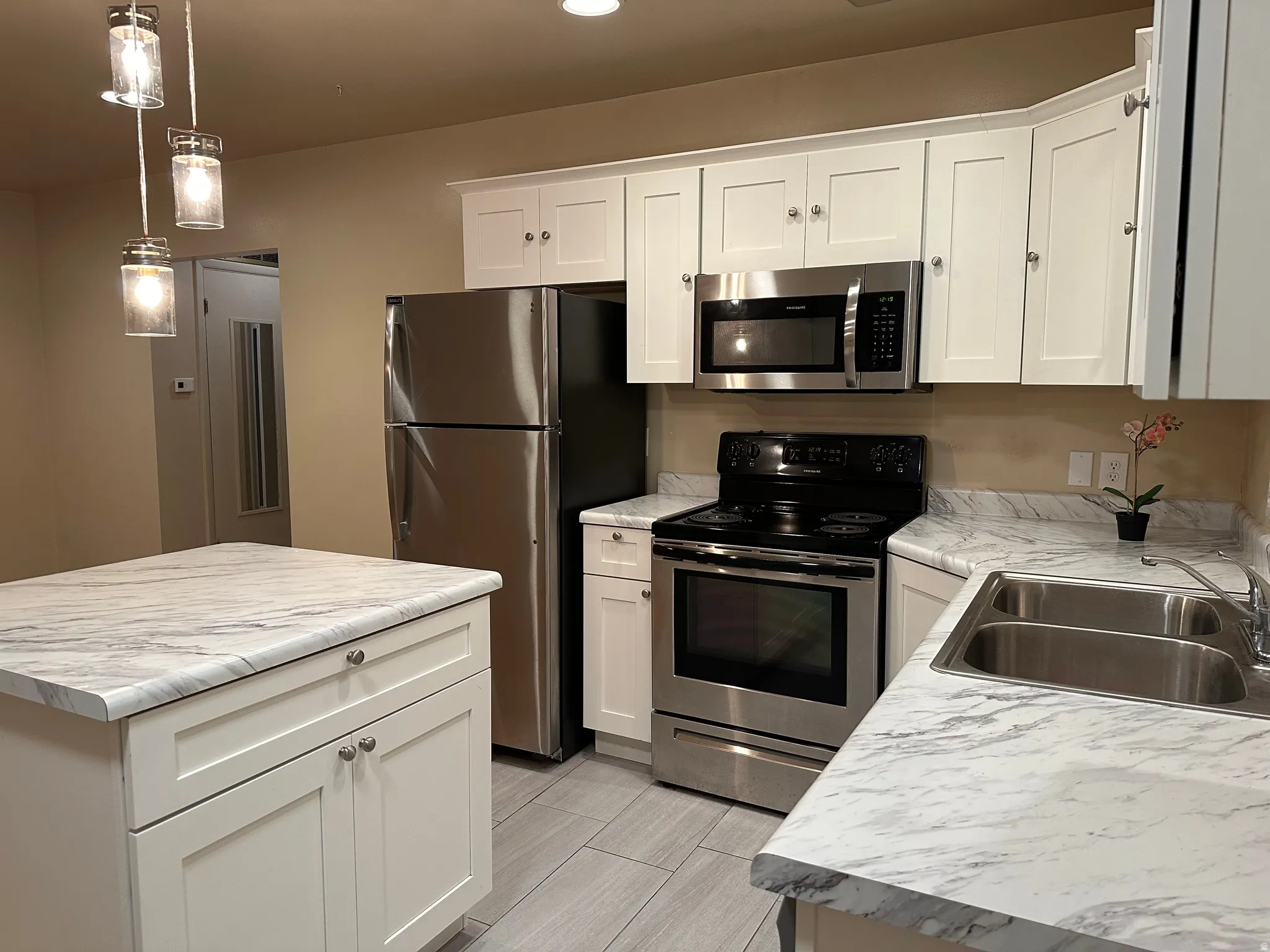 Kitchen featuring white shaker-style cabinetry, a central island with storage, stainless steel appliances, and wood-finish flooring