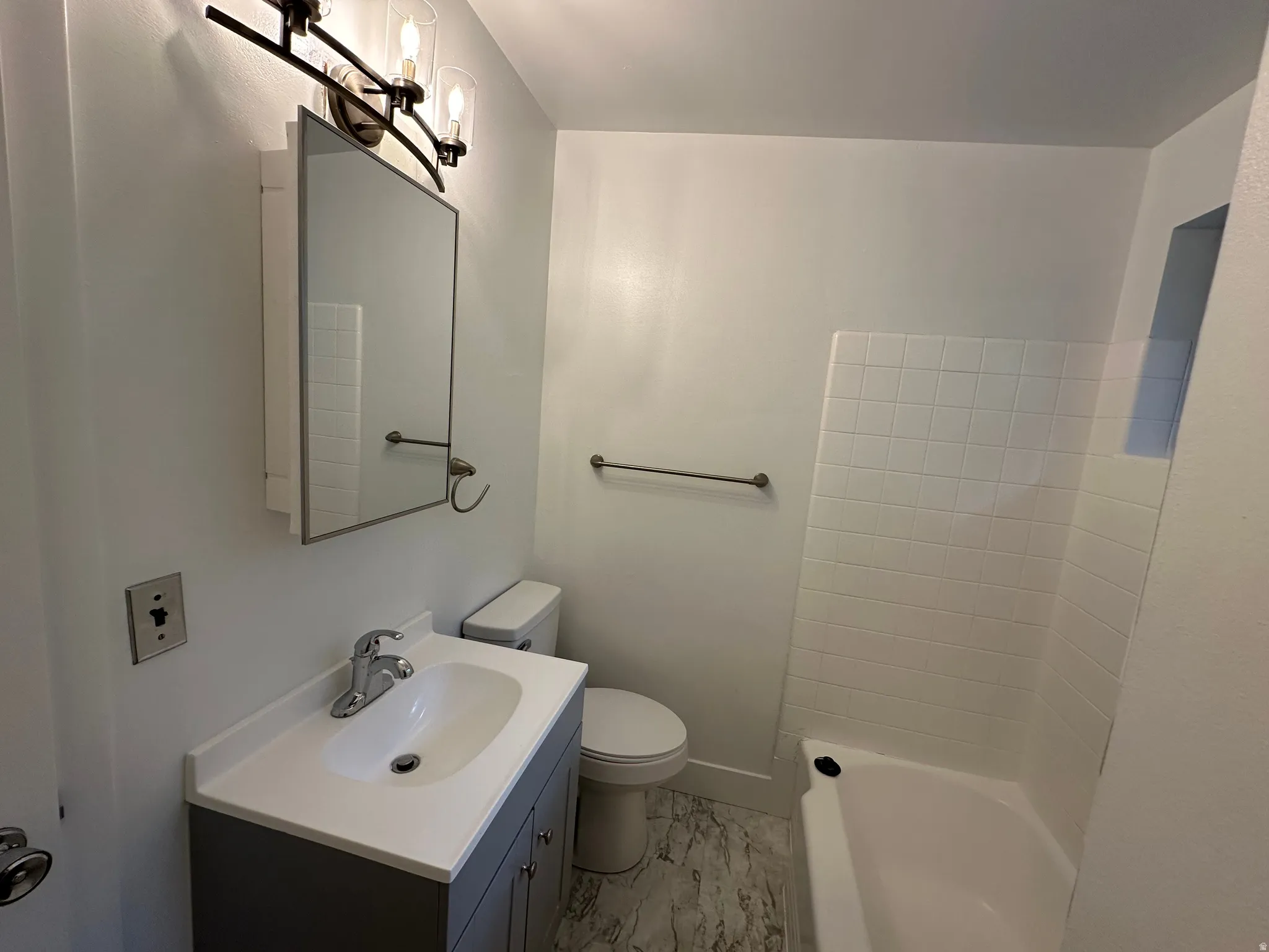 Bathroom featuring a contemporary vanity with an integrated sink, polished chrome faucet, and dark gray cabinetry