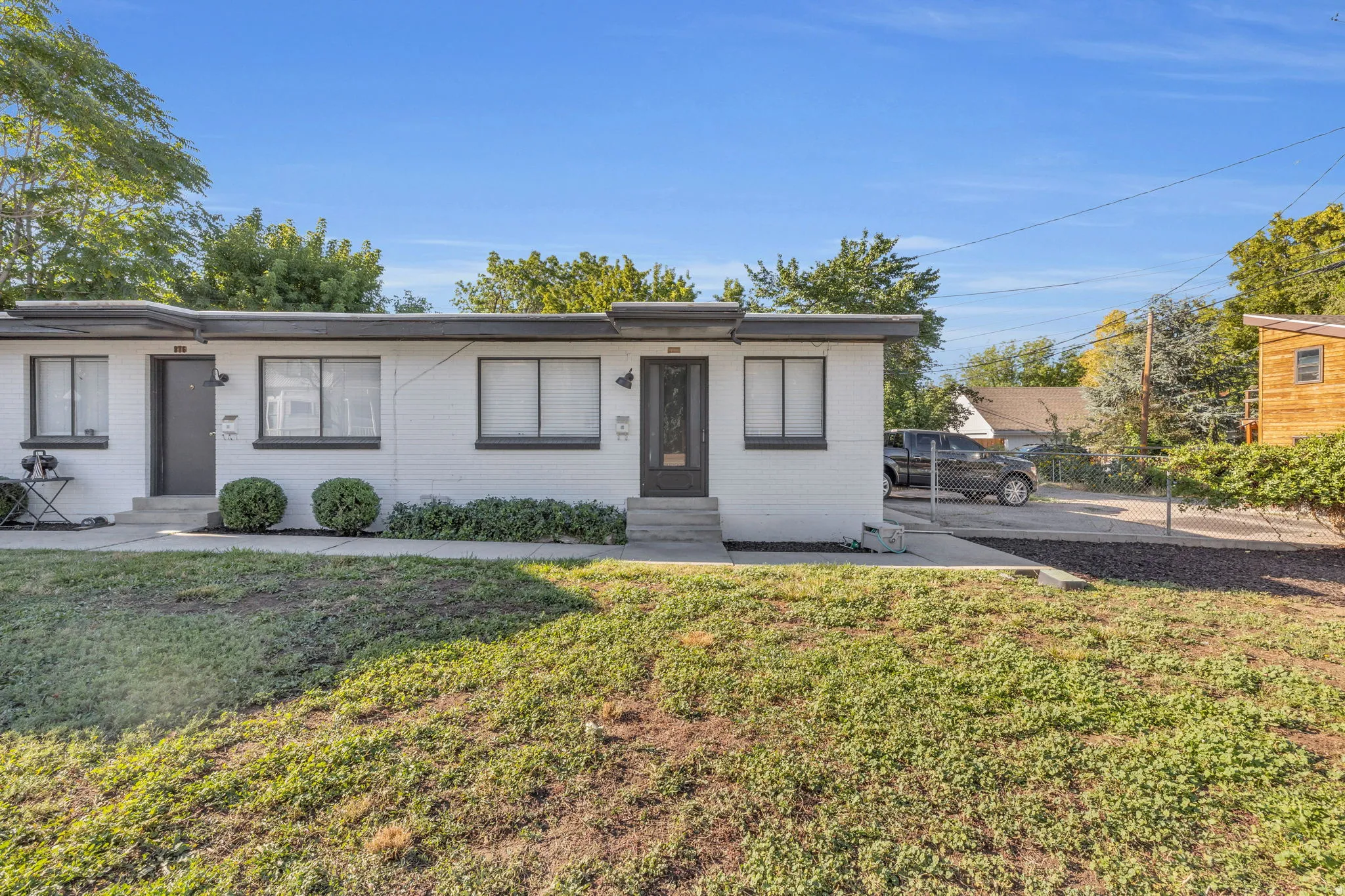 Modern multi-unit property with a white brick exterior, dark trim, and individual entryways