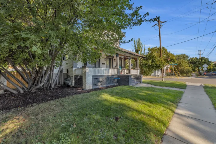 Inviting front porch with decorative railing, surrounded by mature trees and manicured lawn