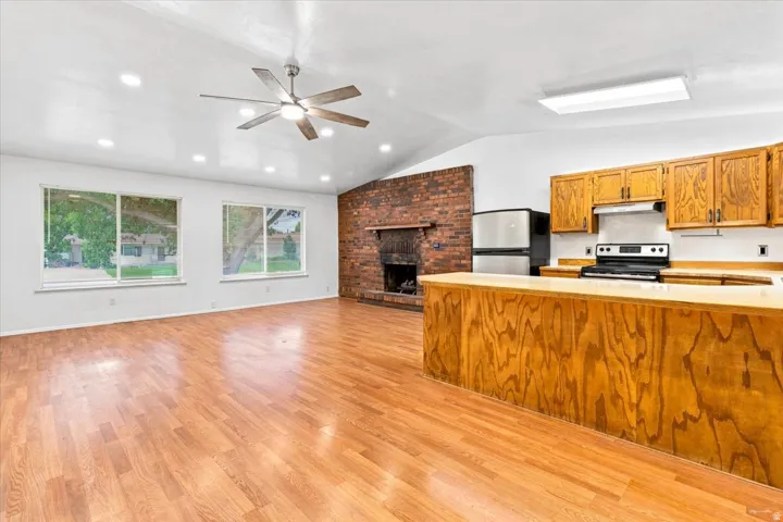 Open-concept living area featuring wood-finish flooring, a vaulted ceiling, and recessed lighting