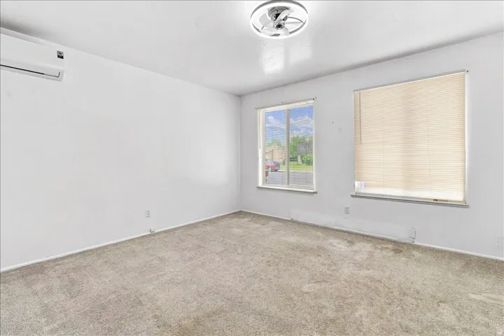 Neutral gray carpeting, two windows, and a ceiling-mounted light fixture
