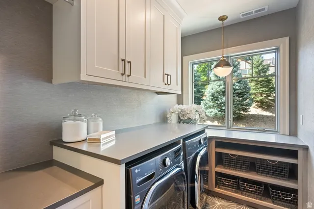 Dedicated laundry area featuring white shaker-style cabinetry, a built-in countertop, and a window providing natural illumination
