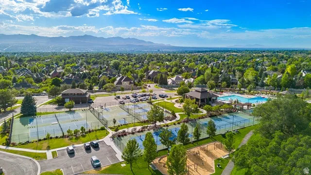 Community recreation area featuring multiple tennis courts, a large swimming pool, a shaded pavilion, and a children's play area