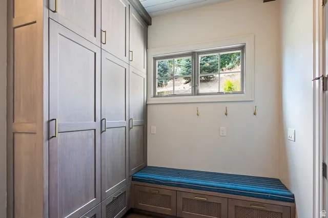 Built-in cabinetry with brass hardware, integrated bench seating with storage, and a window providing natural illumination