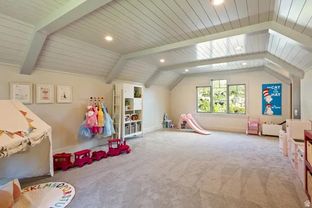 Spacious room featuring vaulted ceilings with exposed beams and shiplap-style paneling, recessed lighting, and light-colored carpeting