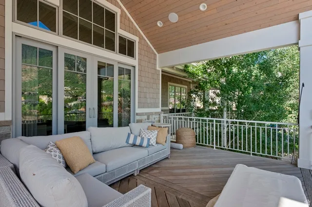 Spacious covered deck featuring wood-finish flooring, a white metal railing, and a tongue-and-groove ceiling with recessed lighting