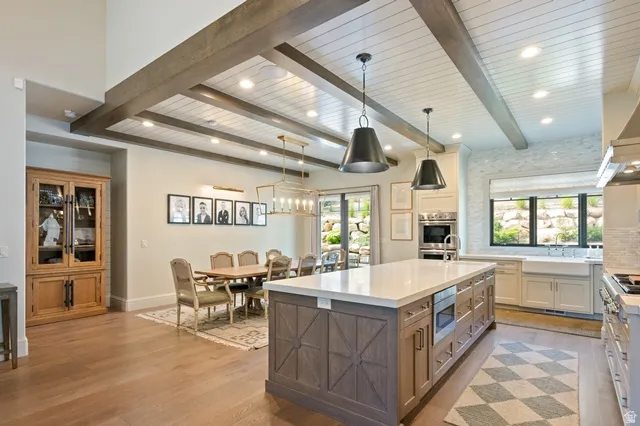 Spacious kitchen and dining area featuring wood-finish flooring, a coffered ceiling with exposed beams, and recessed lighting