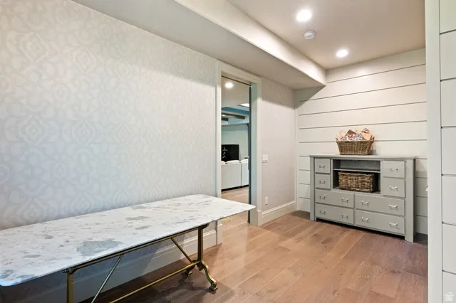 Hardwood-style flooring with patterned accent wall and shiplap paneling