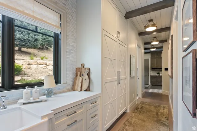 White farmhouse sink set into a white countertop with light wood-finish cabinetry