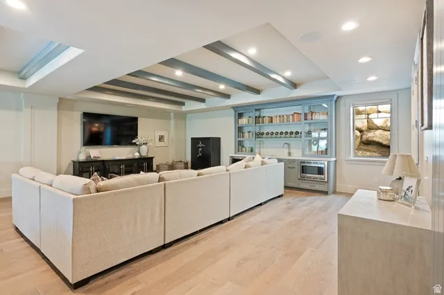 Spacious room featuring light wood-finish flooring, recessed lighting, and a beamed ceiling