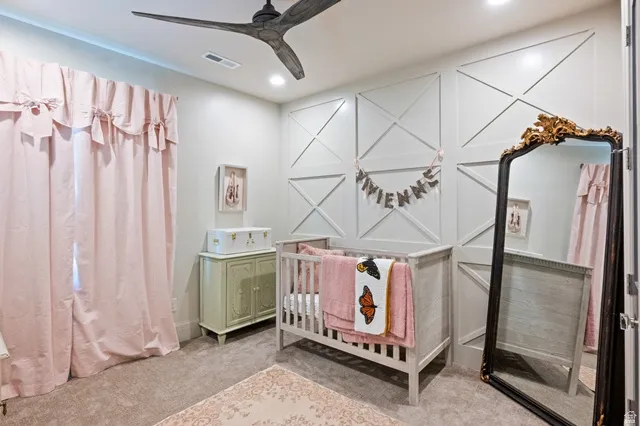 Recessed ceiling lighting illuminates the room, featuring a modern ceiling fan and decorative wainscoting on the far wall