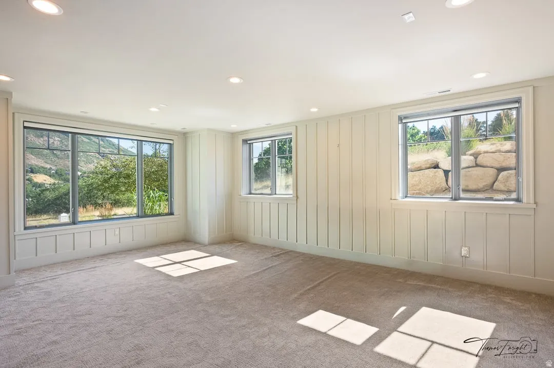 Spacious room featuring board and batten wainscoting, recessed lighting, and light-toned carpeting