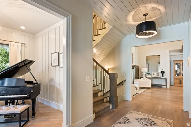 Entryway featuring hardwood flooring, an open staircase with metal balusters, and a paneled ceiling with a decorative pendant light