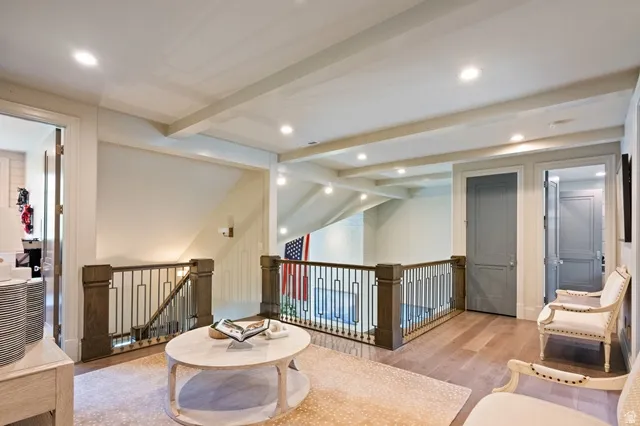 Upper-level landing featuring wood-finish flooring, recessed lighting, and exposed ceiling beams