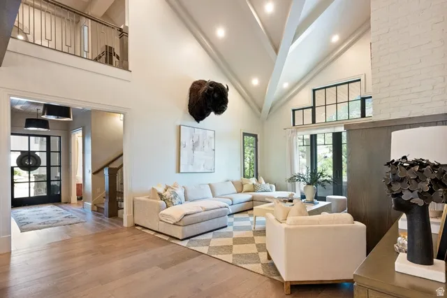 Spacious living area featuring a vaulted ceiling with exposed beams, recessed lighting, and wood-finish flooring