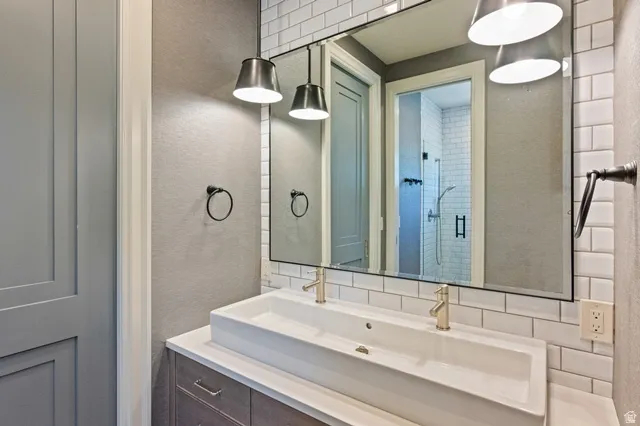 Bathroom vanity featuring a dual vessel sink, gold-finish faucets, and a full-width mirror
