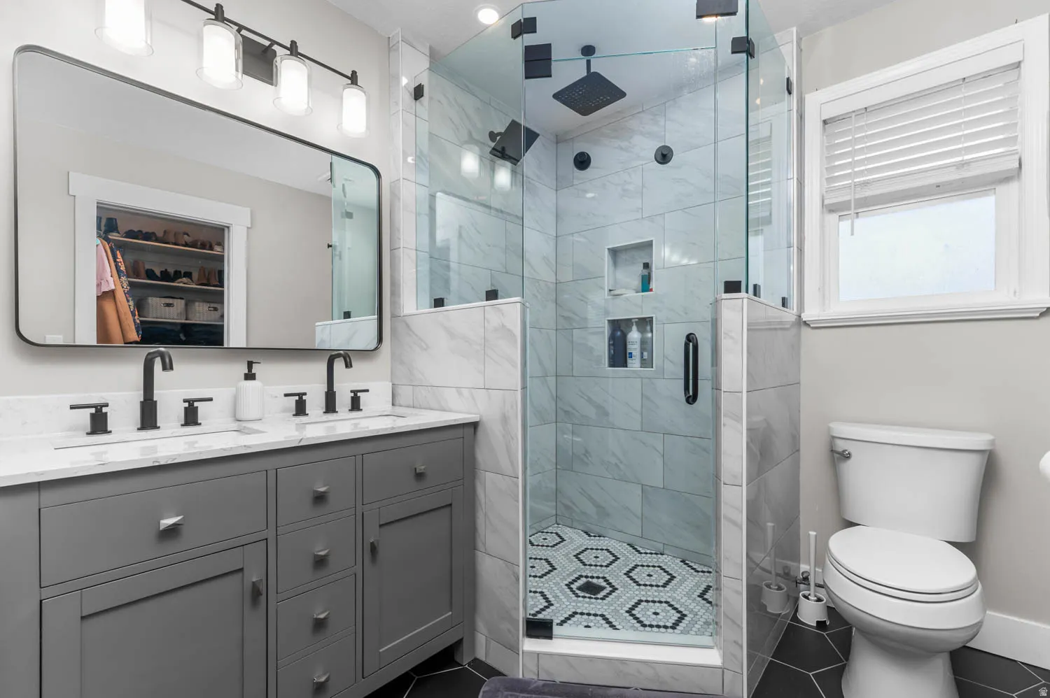 Custom shower featuring a patterned hexagon tile floor, full-height glass enclosure, and dual shower heads