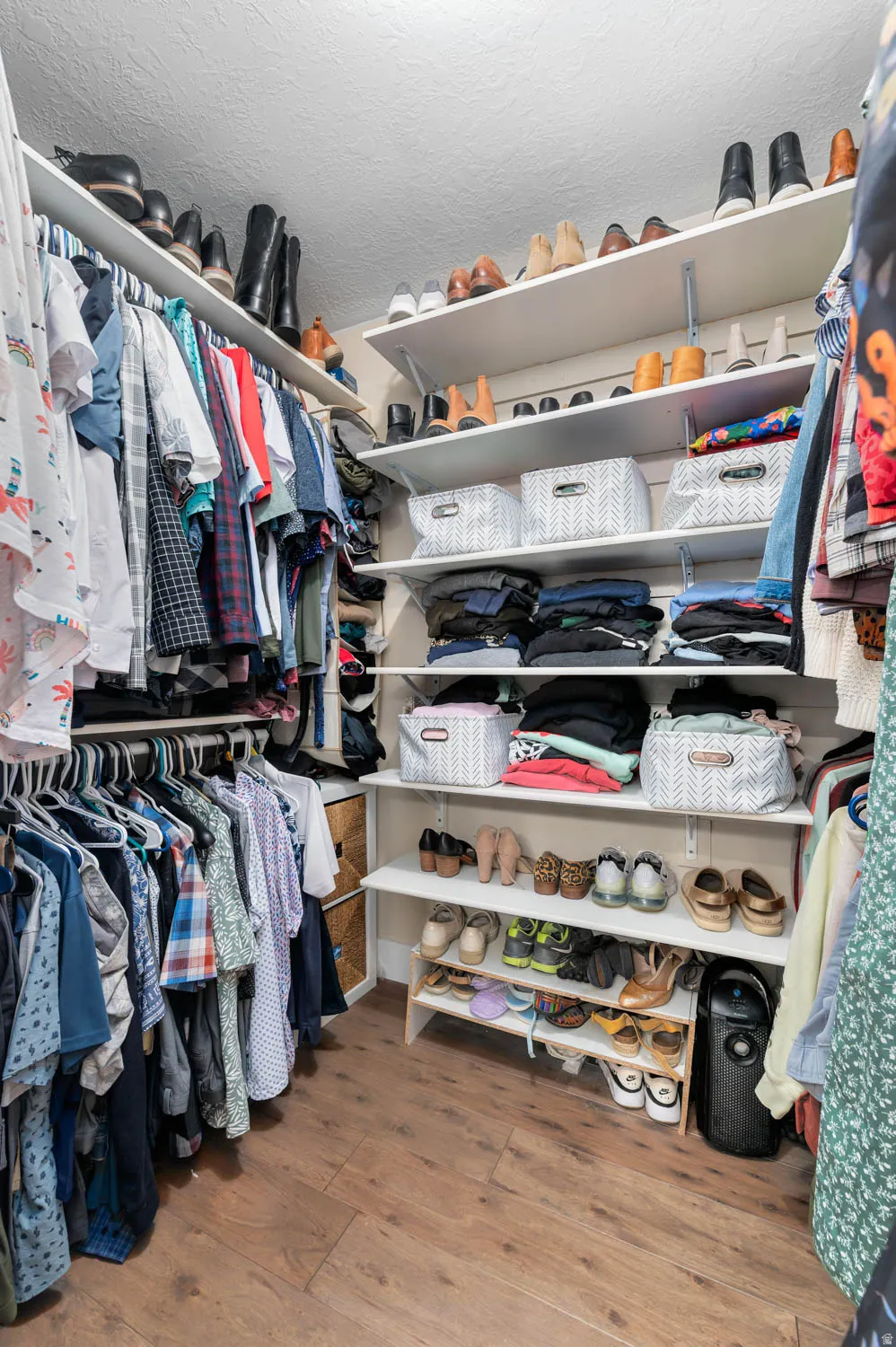 Expansive custom closet featuring wood-finish flooring, multiple hanging rods, adjustable shelving, and recessed lighting