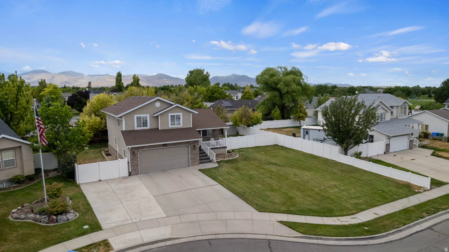 Two-story residential property featuring a neutral-toned exterior with stone accents, an attached two-car garage, and a concrete driveway