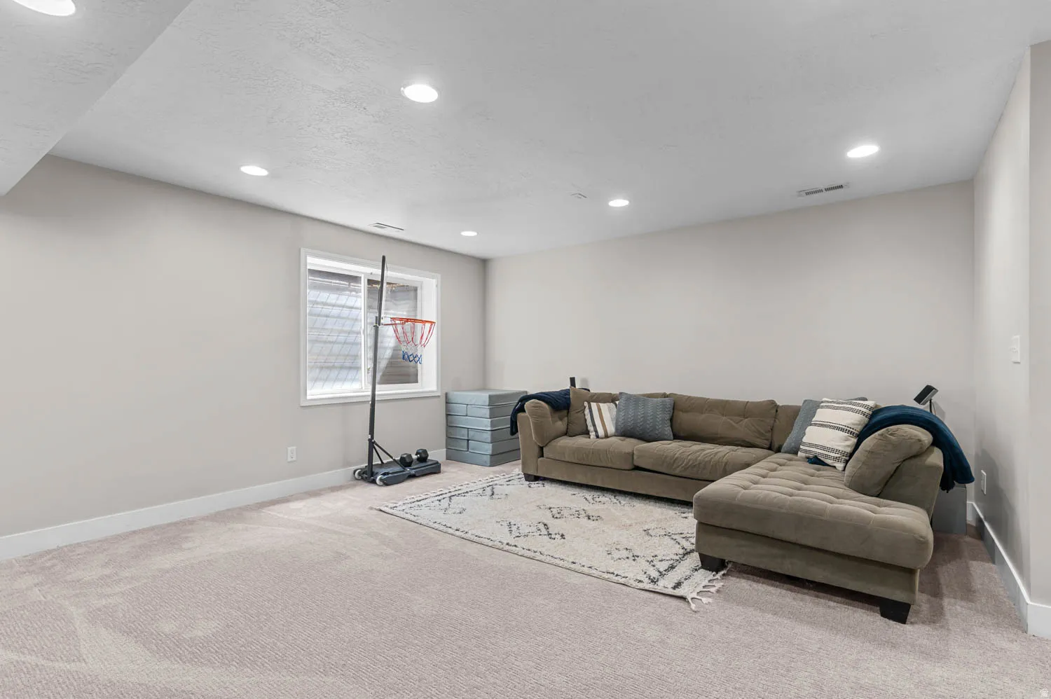 Spacious carpeted room featuring recessed lighting, a sliding window with a window well, and light-toned wall paint