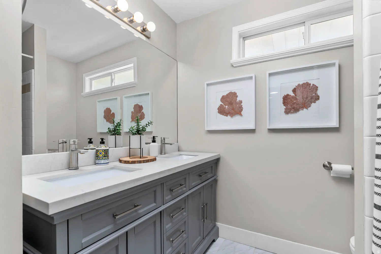 Dual vanity featuring two integrated sinks, a white countertop, and gray shaker-style cabinetry with chrome hardware