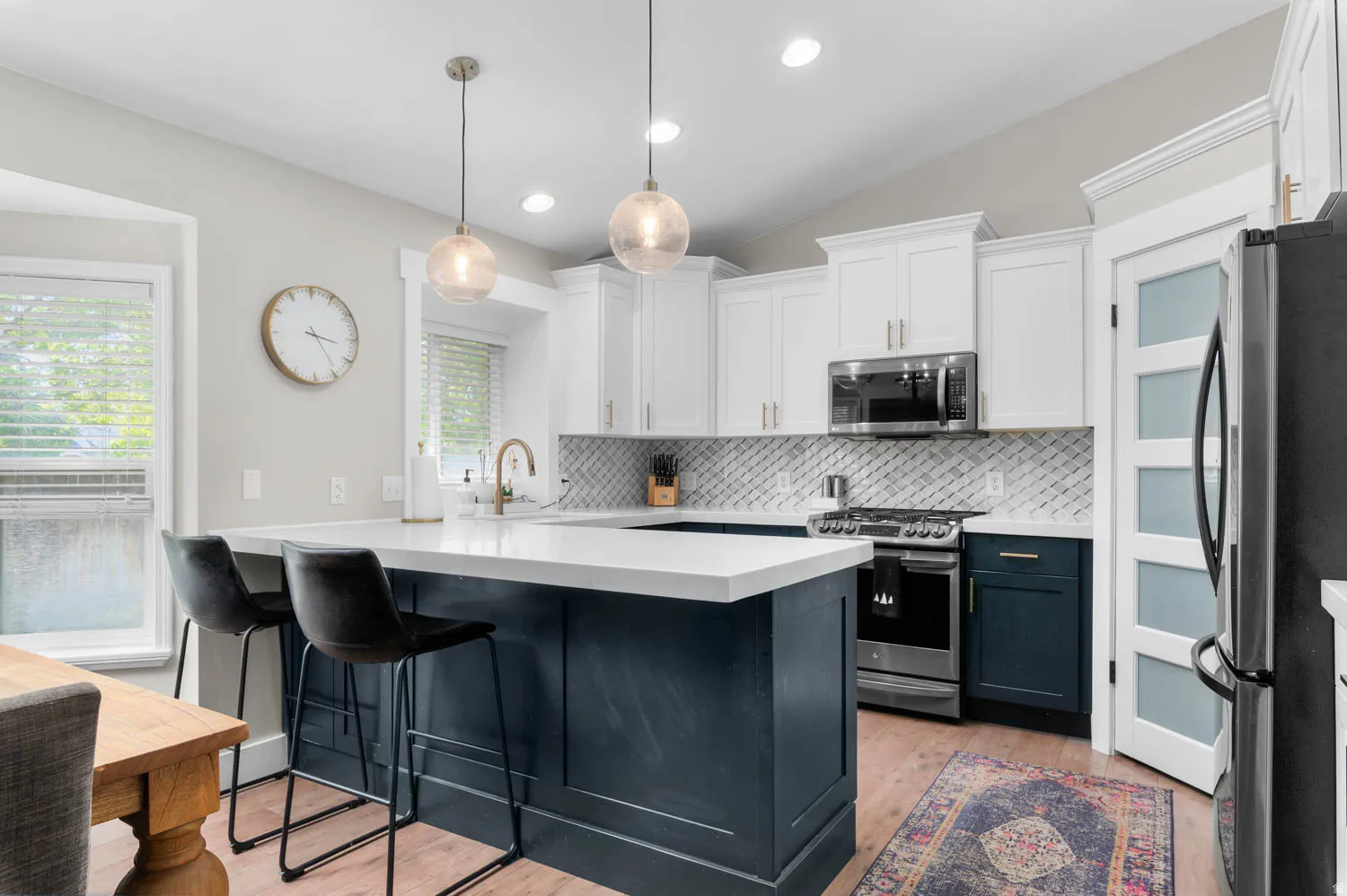 Kitchen featuring a two-tone cabinetry design, stainless steel appliances, a white quartz countertop, and a diagonal tile backsplash