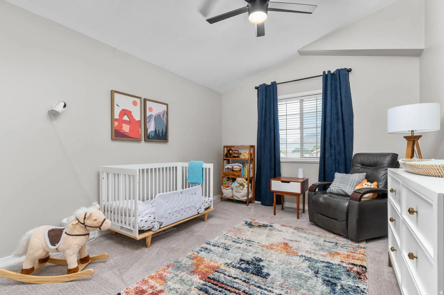 Carpeted room featuring a ceiling fan, vaulted ceiling, and window with blinds