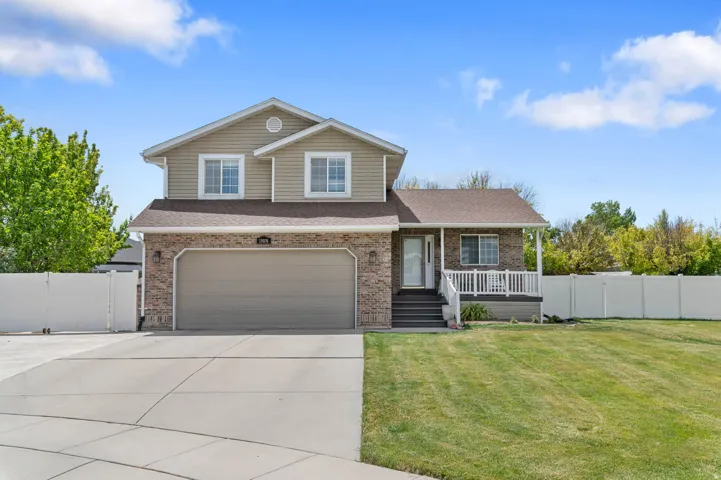 Two-story residence featuring a brick and siding exterior, an attached two-car garage, a covered front porch with white railings, a concrete driveway, and a front lawn