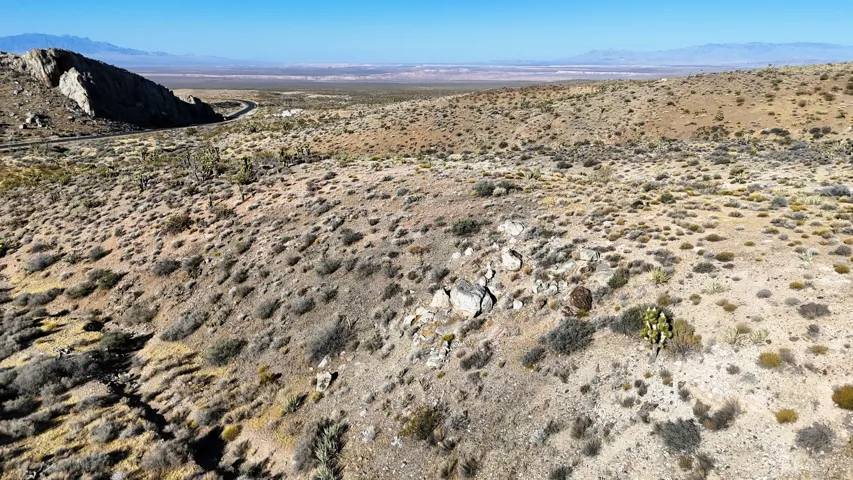Expansive desert terrain featuring varied elevation, natural rock formations, and sparse vegetation