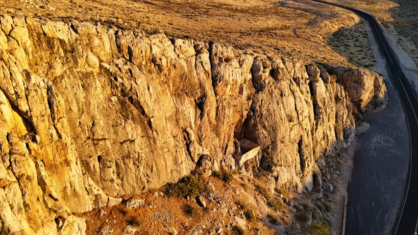 Natural rock cliff formation bordering an asphalt road