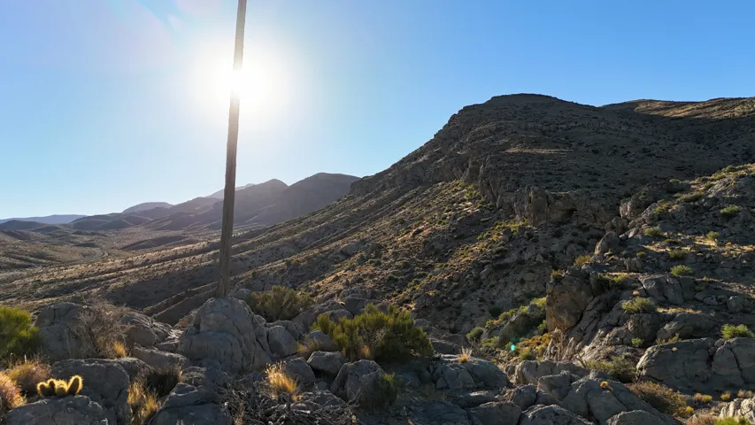 Expansive desert landscape featuring rugged mountain terrain, natural rock formations, and arid vegetation under a clear sky