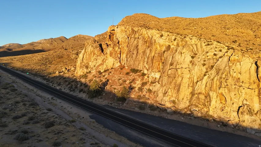 Expansive desert landscape featuring a prominent rock formation and a paved roadway