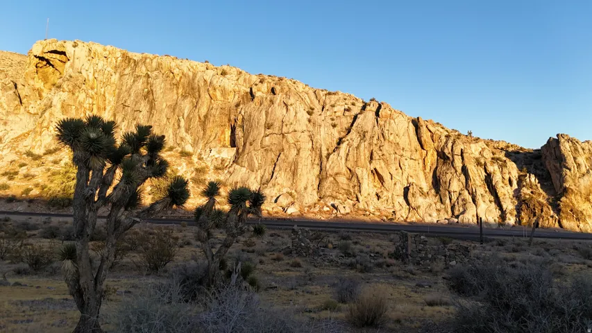 Desert landscape featuring a prominent rock formation, sparse native vegetation, and a clear horizon