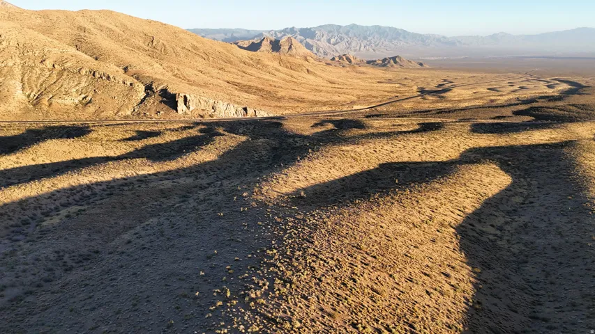 Expansive desert landscape with natural terrain, rugged mountains, and distant flatlands