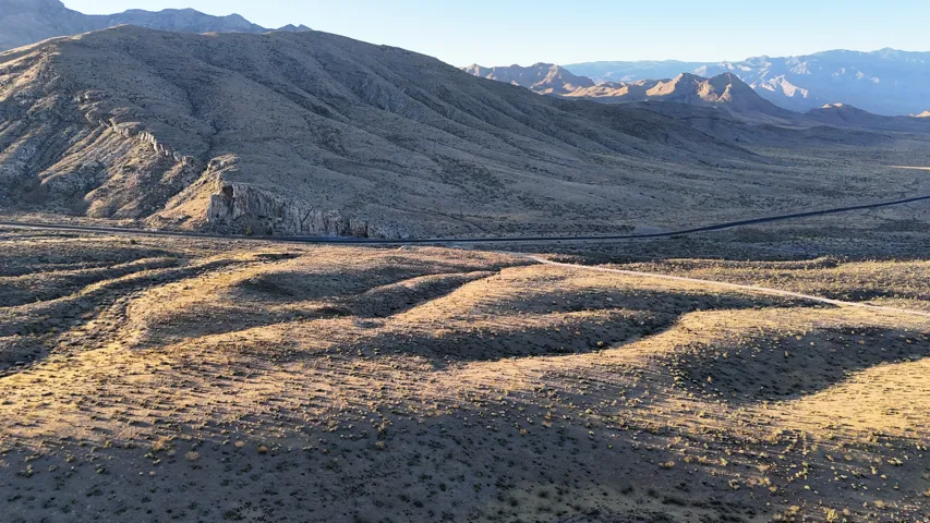 Expansive desert landscape featuring undulating terrain and distant mountain ranges