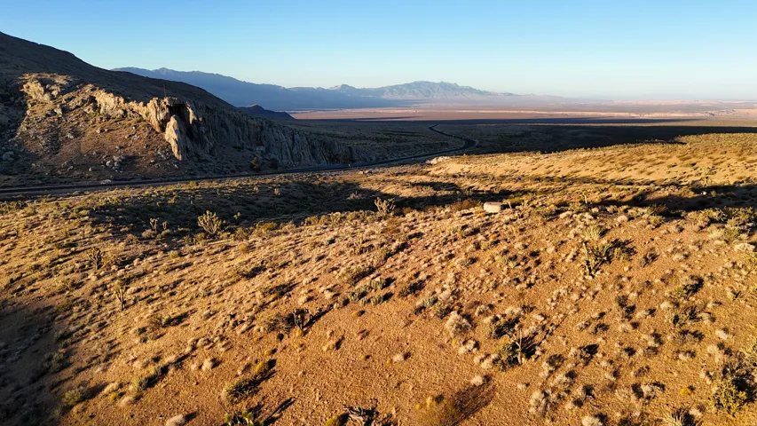 Expansive desert landscape featuring natural rock formations and distant mountain ranges under a clear sky