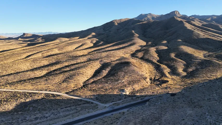 Expansive desert landscape featuring rolling terrain and distant mountain ranges under a clear sky