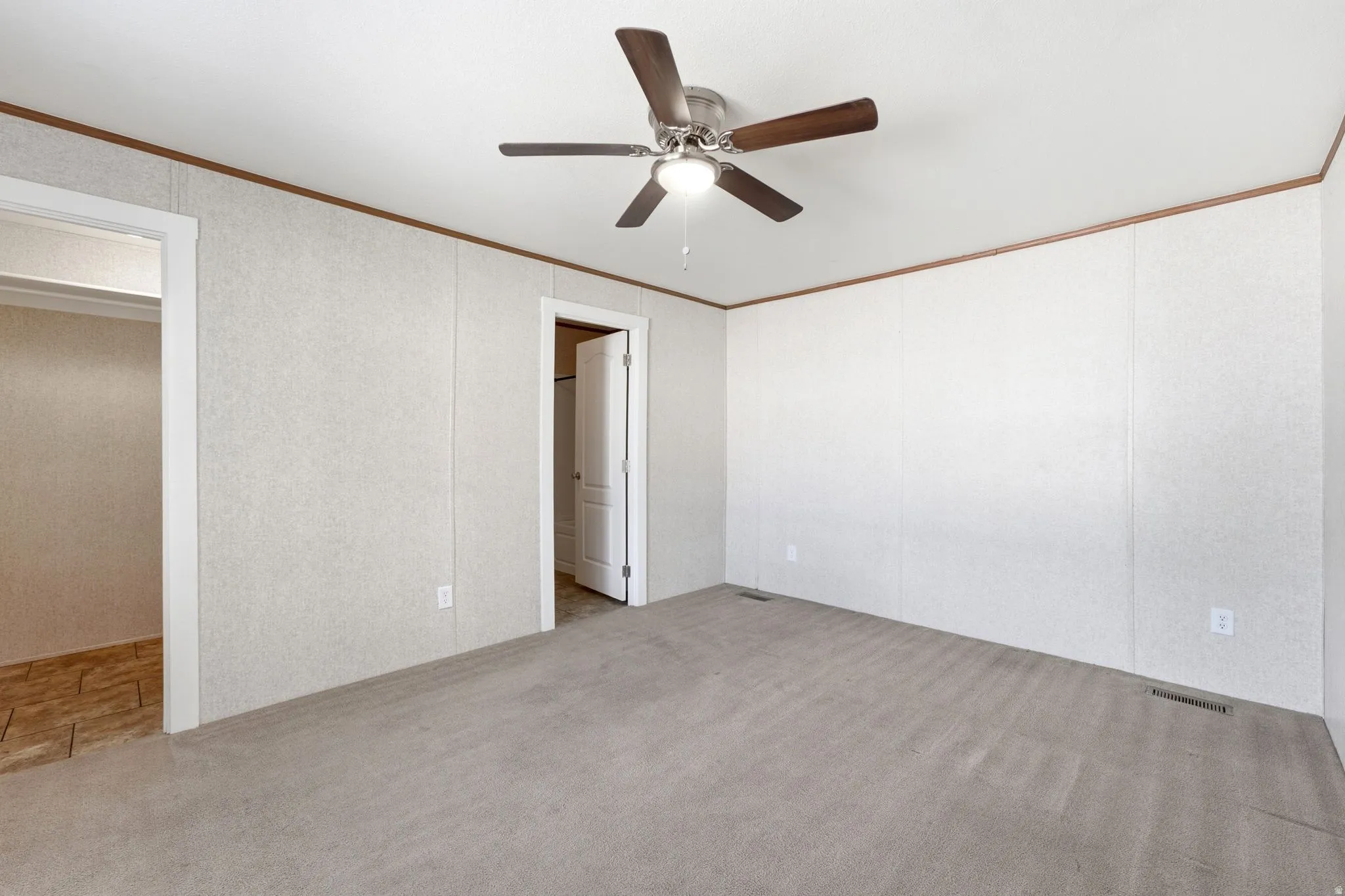 Carpeted interior space with a ceiling fan featuring wood-look blades and a central light fixture