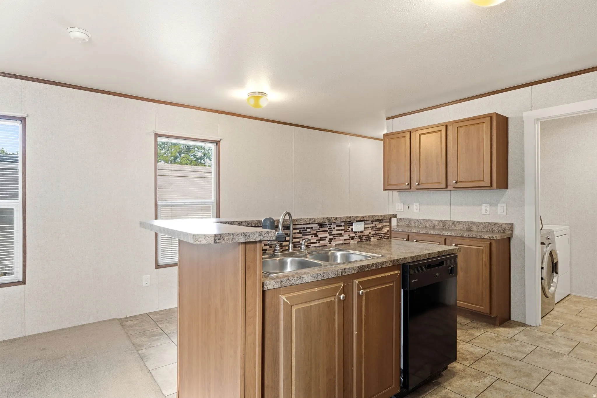 Kitchen featuring an L-shaped counter with a dual basin sink, integrated dishwasher, and wood-finish cabinetry