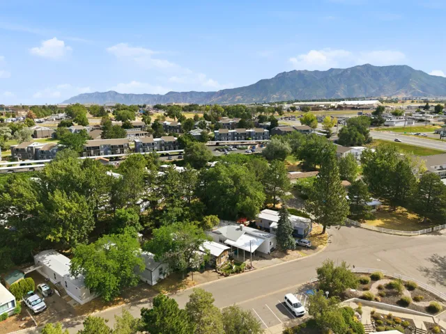 Expansive aerial view showcasing residential properties, surrounding green spaces, and distant mountain ranges