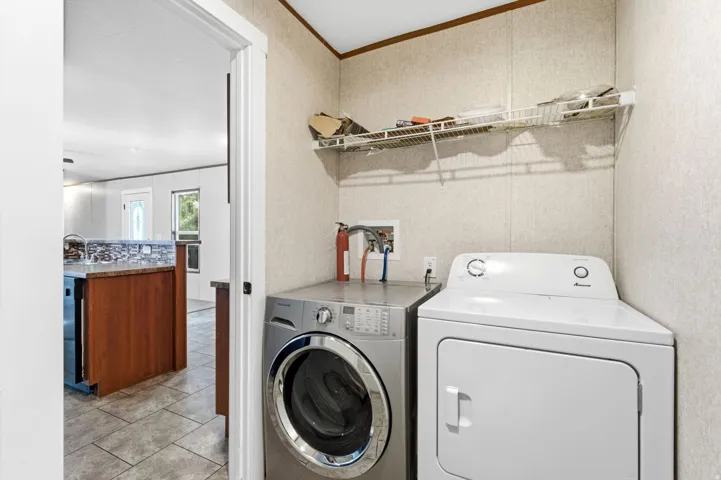 Dedicated laundry area featuring a wire storage shelf, textured wall panels, and wood-trim accents