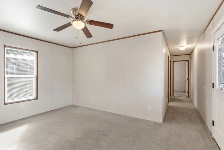 Interior room featuring light gray carpet, white wall panels, and dark wood-finish trim