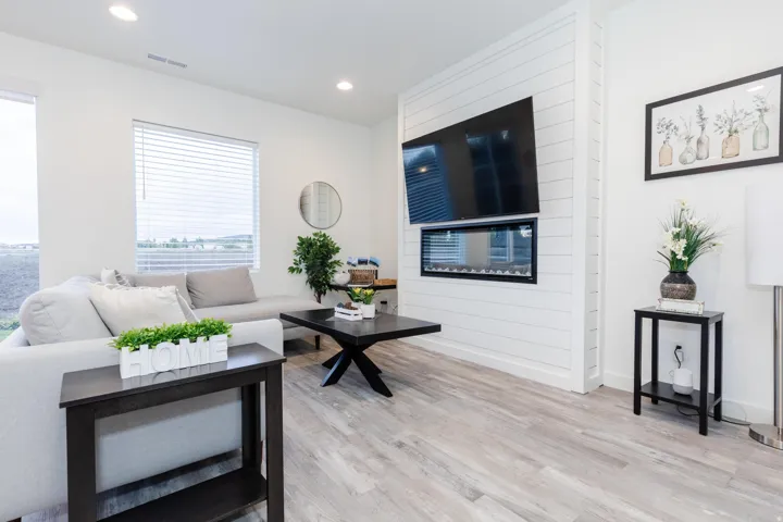 Living area featuring wood-finish flooring, recessed lighting, and a prominent shiplap accent wall with a built-in linear electric fireplace