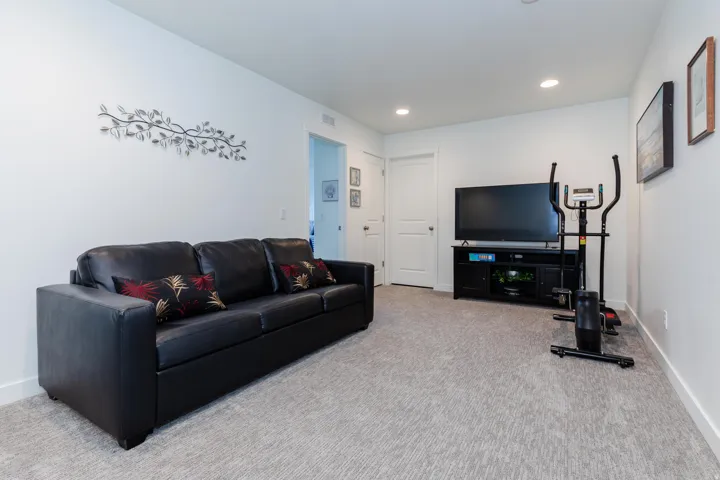 Spacious room featuring light gray patterned carpeting, white walls, and recessed ceiling lighting