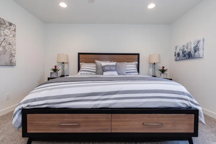 Spacious bedroom featuring light-colored walls, recessed ceiling lighting, and carpet flooring